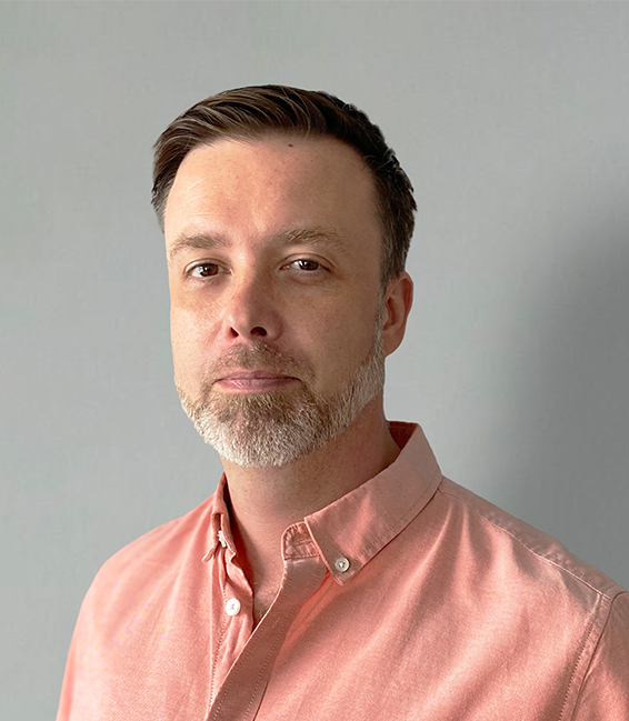 a man is looking at the camera whilst wearing a salmon coloured shirt